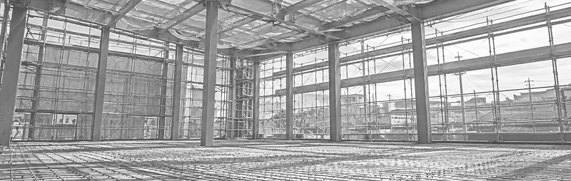 鉄骨の柱と梁が組み上がり、足場に囲まれた建設中の建物内部