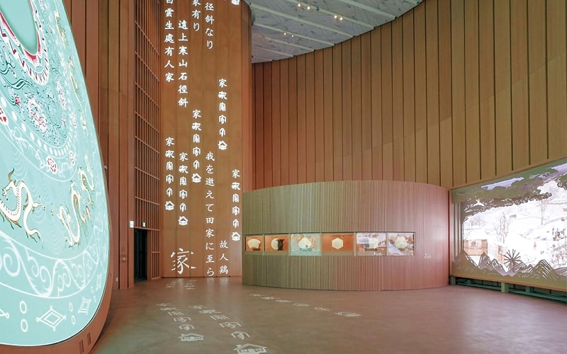 竹の文様が描かれた大型の曲面壁と、展示ケースが並ぶ館内