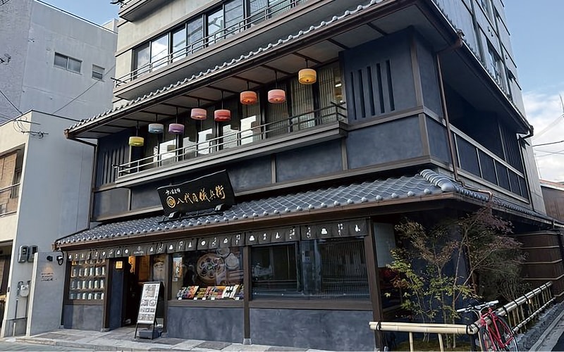 瓦の庇と提灯で彩られた和の外観と、1階の店舗の入口